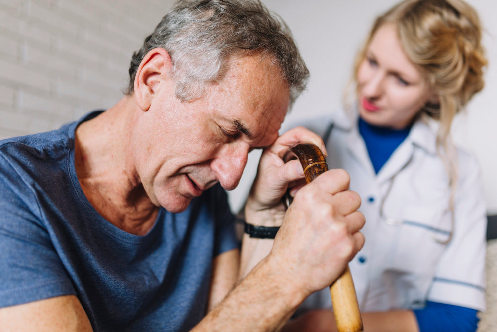 A senior man feeling distressed while holding a cane, with a compassionate nurse providing support