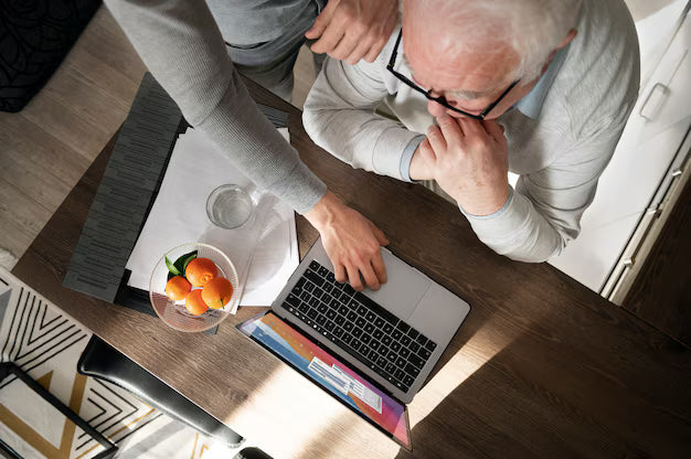 Grandparent being guided to use a digital device,  showing intergenerational assistance, patience, and tech adaptation for older adults