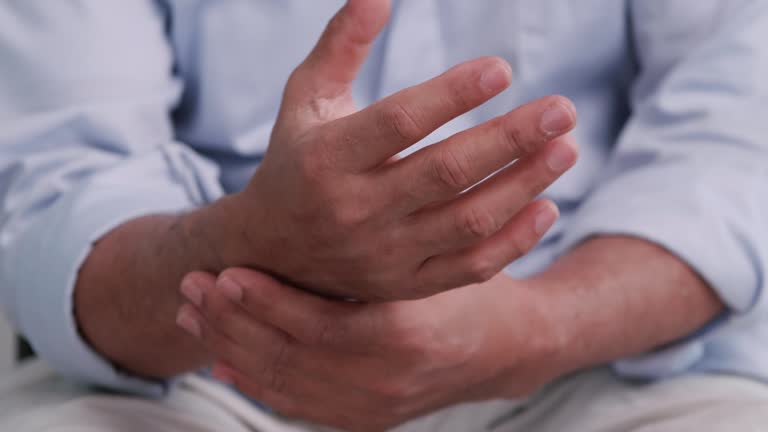 Close-up of a man holding and rubbing his wrist, indicating wrist pain, joint discomfort, or possible repetitive strain injury.