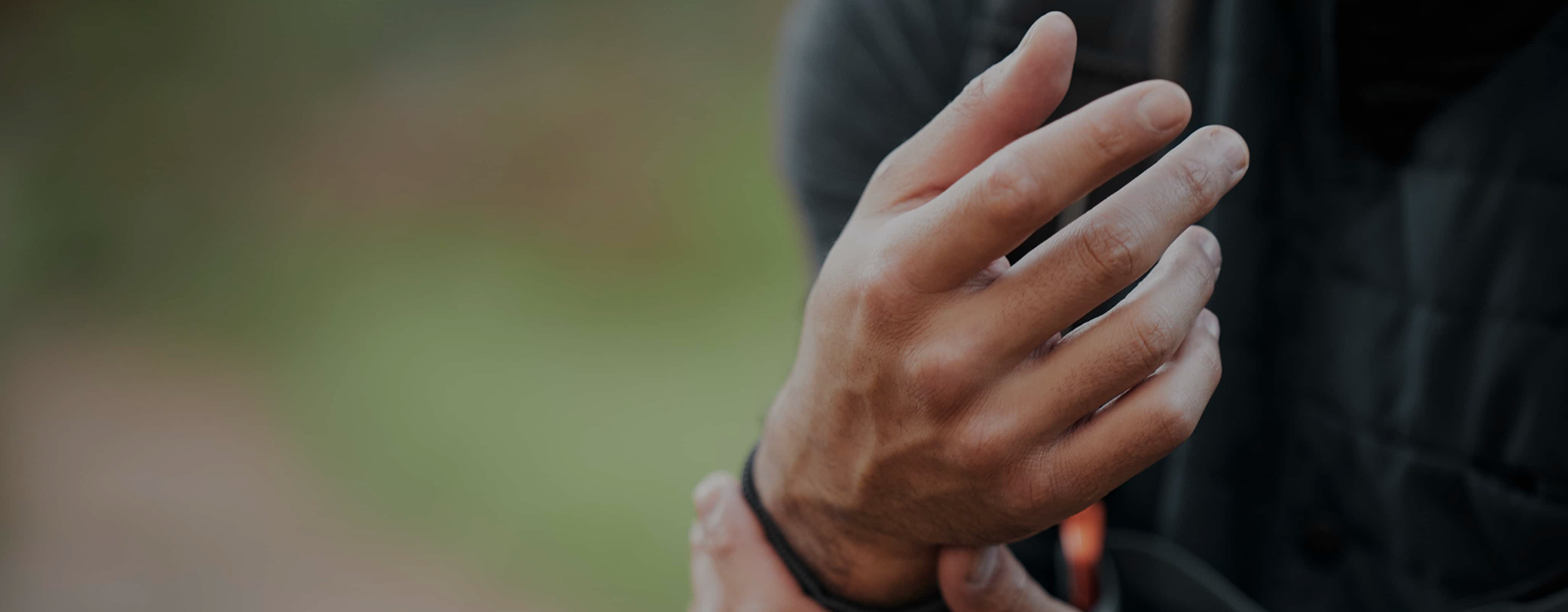 A close-up shot of a person's hand wearing a black knit glove, set against a softly blurred outdoor background.