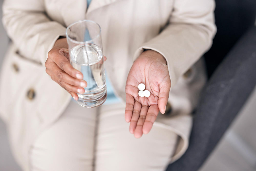Propranolol for Essential Tremor, where a woman is holding medication pills with a glass of water.