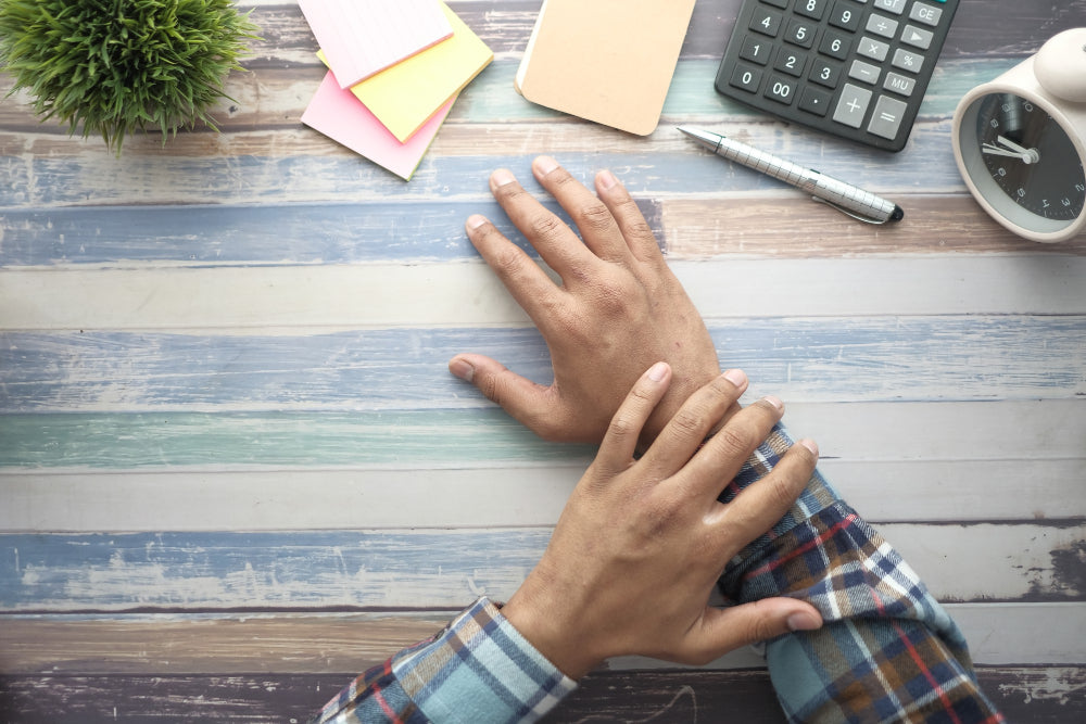 A person resting their hands on a desk workspace, illustrating daily life and routines while living with essential tremor.