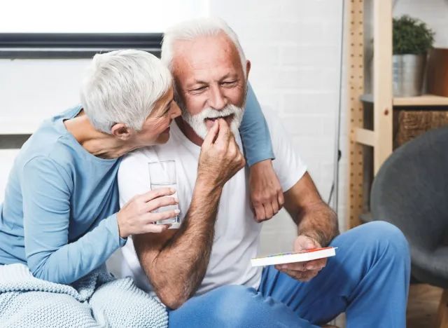 A caregiver assists an elderly man with mobility, illustrating the importance of managing carbidopa/levodopa side effects.