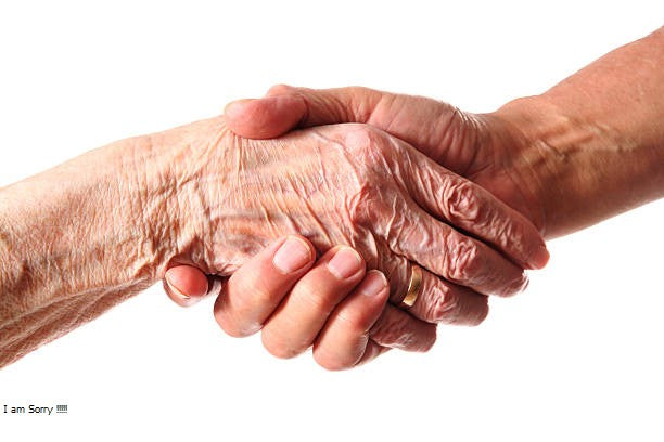 Closeup of two elderly hands holding each other, fingers intertwined, showing signs of feeling shaky and weak.