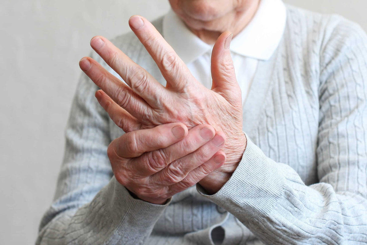 Senior woman experiencing hand tremors, a common early sign of Parkinson's Disease or Essential Tremor.