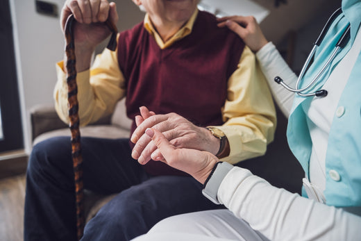 A nurse assisting an elderly man at home, highlighting care in the history of Parkinson's disease.