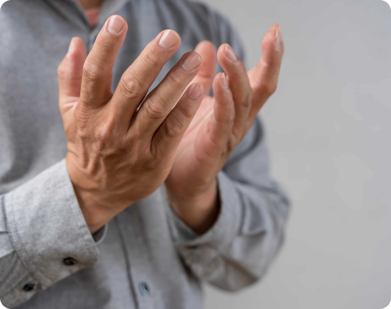 A person clasping hands together outdoors due to visible shaking, representing shaky hands causes