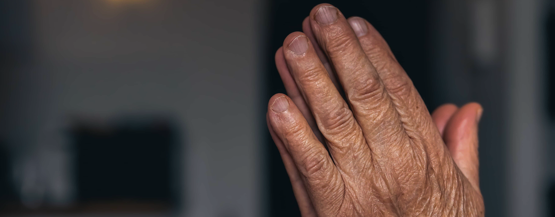 A person holding one hand with the other while experiencing tremor, illustrating why my hands are shaking
